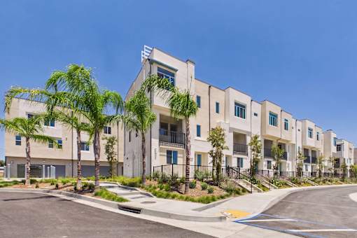 A row of modern apartment buildings with trees in front.