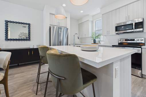 A modern kitchen with a large island and two chairs.