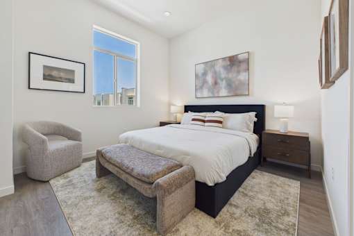 A bedroom with a large bed and a chair.
