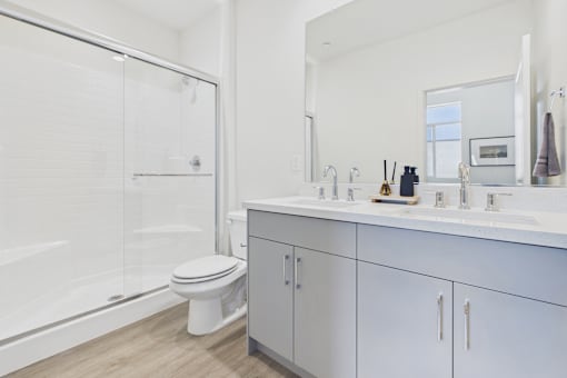 A white bathroom with a toilet, sink, and shower.