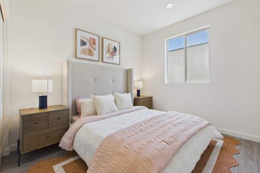 A bedroom with a large bed, a dresser, and two framed pictures on the wall.