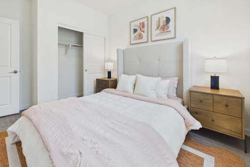 A bedroom with a large bed and a wooden nightstand.