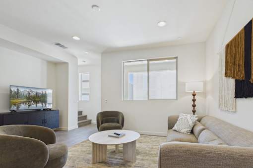 A living room with a couch, chairs, and a television.