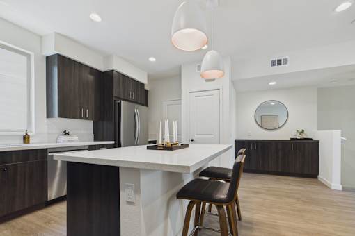 A modern kitchen with a white island and dark wood cabinets.