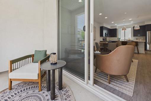 A modern living room with a glass door leading to a kitchen.