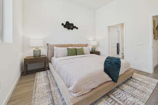A bedroom with a large bed and a wooden nightstand.