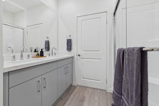 A bathroom with a white door and a grey towel hanging on a towel rack.