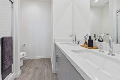A bathroom with a white counter top and a towel hanging on the door.