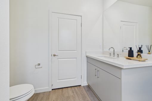 A white bathroom with a toilet, sink, and mirror.