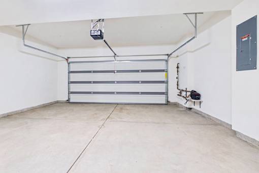 A garage with a white wall and a closed white door.