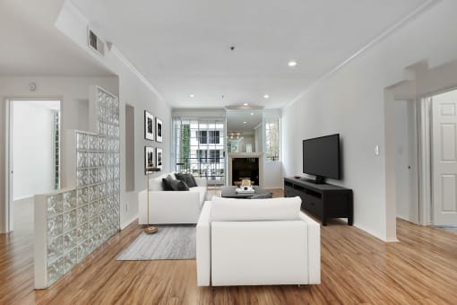 a living room with two white couches and a tv