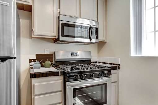 A modern kitchen with a stove, microwave, and refrigerator.