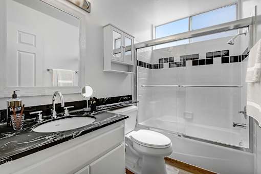 A white toilet sits in a bathroom with a marble counter top.