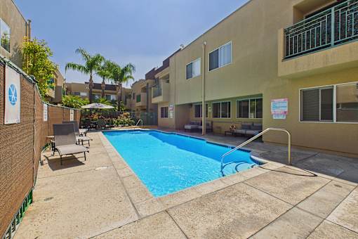 A small pool surrounded by a concrete patio and a building.