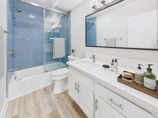 A white bathroom with a blue shower curtain.