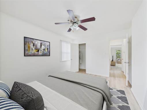 A bedroom with a bed and a ceiling fan.