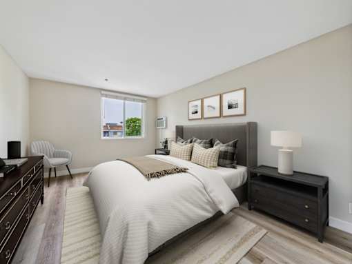 A bedroom with a large bed and a chair.