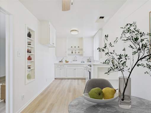 A kitchen with a table holding a bowl of fruit.