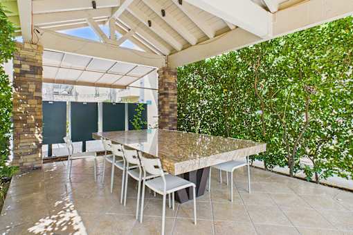 A patio with a table and chairs is surrounded by greenery.