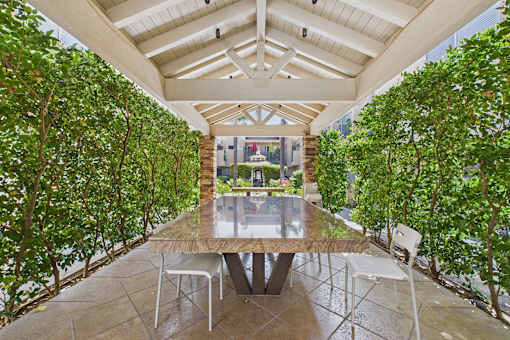 A table surrounded by chairs in a greenhouse.