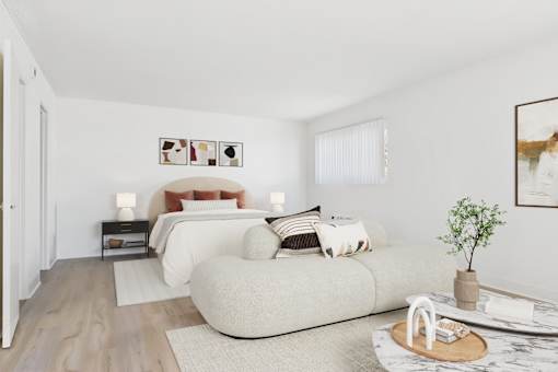 A modern bedroom with a large bed and a small table with a plant on it.