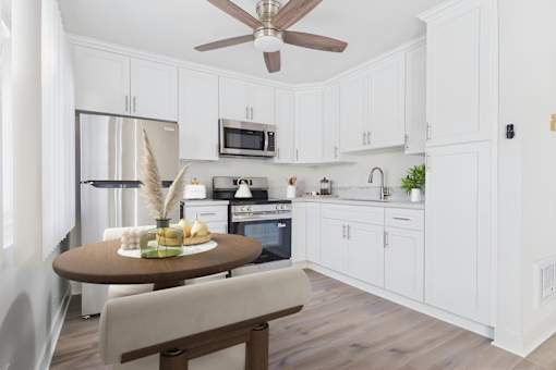 A kitchen with white cabinets and a wooden table.
