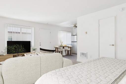 A white couch sits in a living room with a fireplace and a dining table in the background.