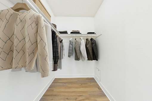 A row of clothes hangs on a rail in a white room.