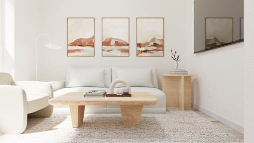 A living room with a white couch, a wooden coffee table, and three landscape paintings on the wall.