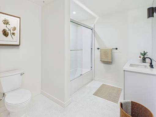 A white bathroom with a toilet, sink, and shower.