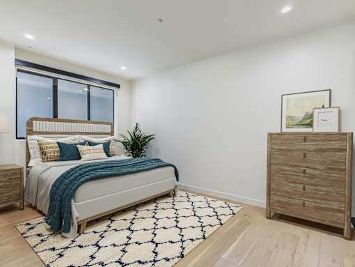 A bedroom with a bed, a dresser, and a rug.