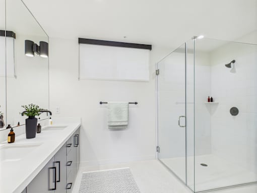 A white bathroom with a glass shower stall and a white sink.