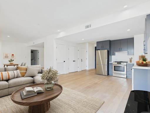 A modern living room with a coffee table and a kitchen in the background.