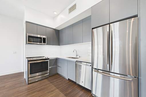 A modern kitchen with stainless steel appliances and wooden flooring.
