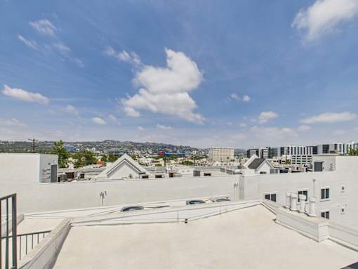 A rooftop with a white building and a cloudy sky.