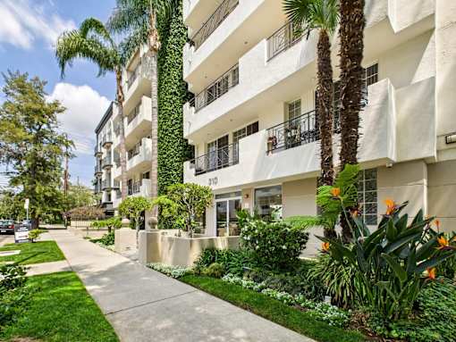 A white apartment building with a green lawn in front.
