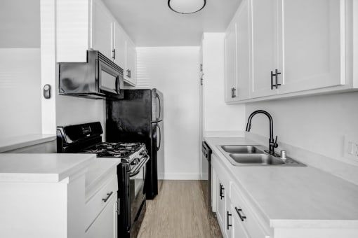 an all white kitchen with black appliances and white cabinets