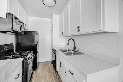 a kitchen with white cabinets and black appliances and a sink
