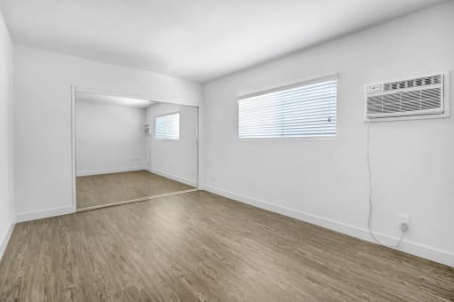 the living room of an empty apartment with white walls and wood floors