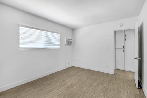 the living room of an apartment with white walls and wood floors
