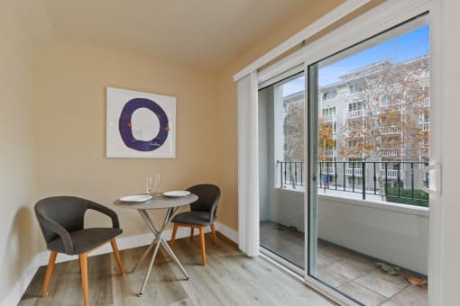 a room with a table and two chairs next to a large window