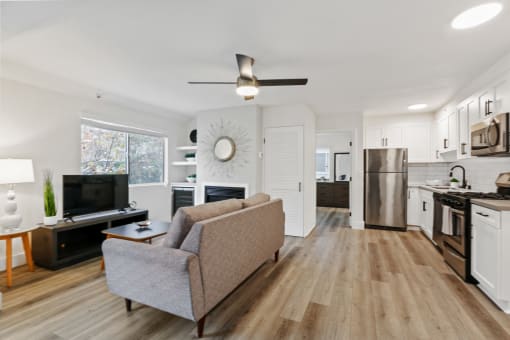 a living room and kitchen with a couch and a tv