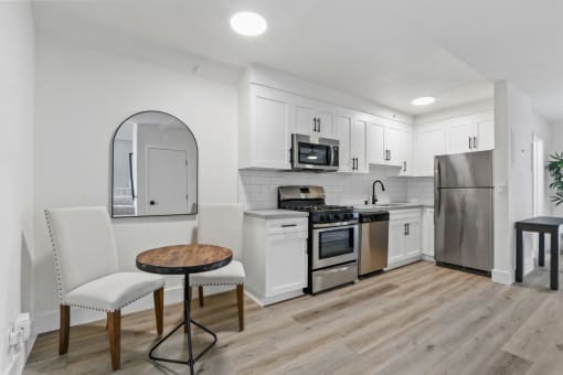 a kitchen with white cabinets and stainless steel appliances and a table