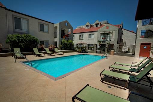 A swimming pool surrounded by lounge chairs and buildings.