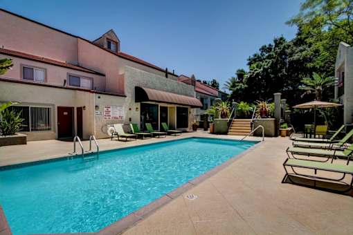 A large outdoor swimming pool with lounge chairs and umbrellas.