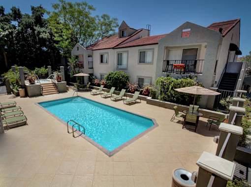 A swimming pool surrounded by a patio with chairs and a table.
