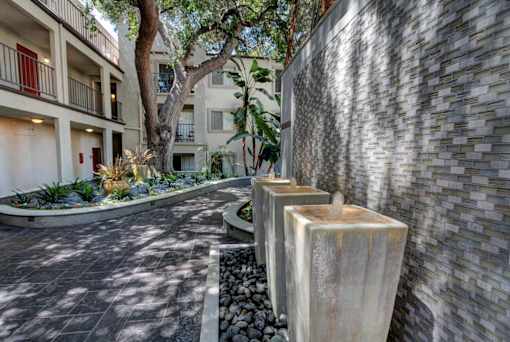 A modern courtyard with a brick wall and a tree.