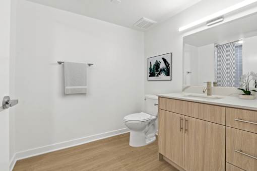 A white bathroom with a toilet, sink, and a picture on the wall.