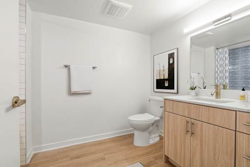A white bathroom with a toilet, sink, and wooden cabinets.