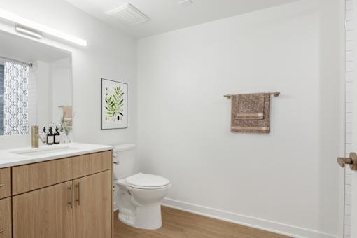 A white toilet sits in a bathroom with a brown towel hanging on the wall.